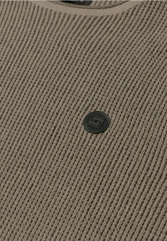 Vue rapprochée d'un vêtement en maille brun clair avec encolure ronde et petit bouton logo sombre.