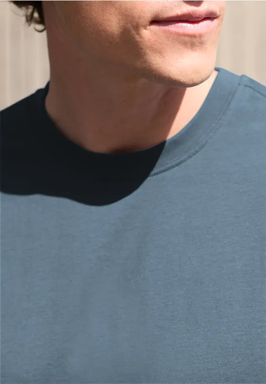 Gedeeltelijke weergave van een man in een blauw T-shirt, nek en onderkant van het gezicht voor een lichte achtergrond