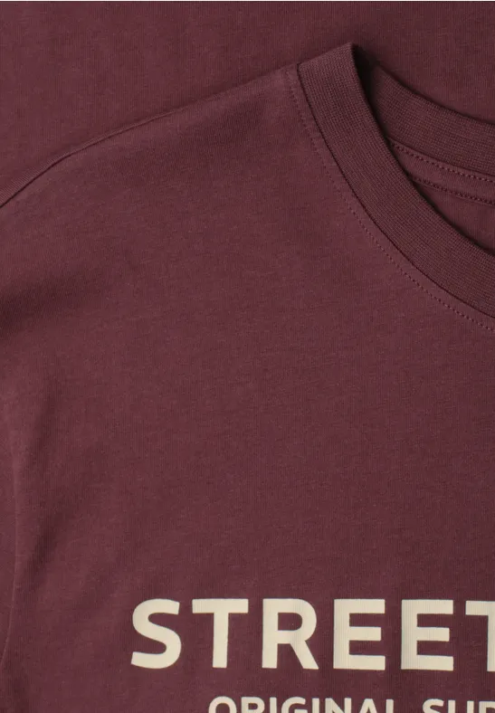 Nahaufnahme eines bordeauxroten T-Shirts mit weißer Aufschrift 'STREET'.