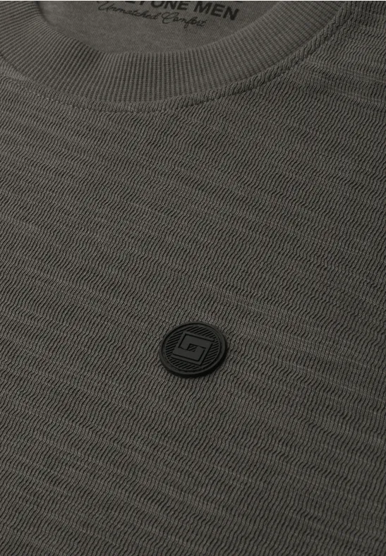 Close-up van een grijs T-shirt met een klein, rond logo op de borst.