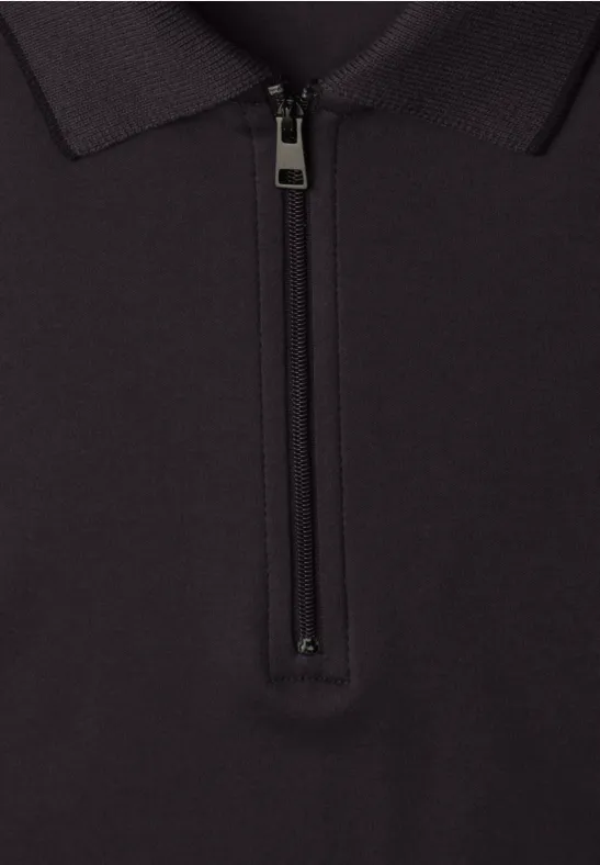 Schwarzes Polo-Shirt mit Reißverschluss am Kragen vor neutralem Hintergrund.