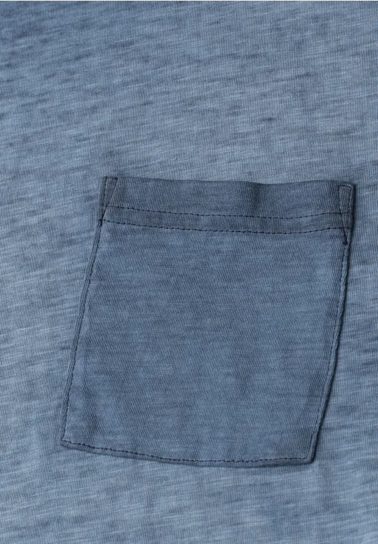 Nahaufnahme eines blaugrauen Stoffes mit einer aufgesetzten Tasche.