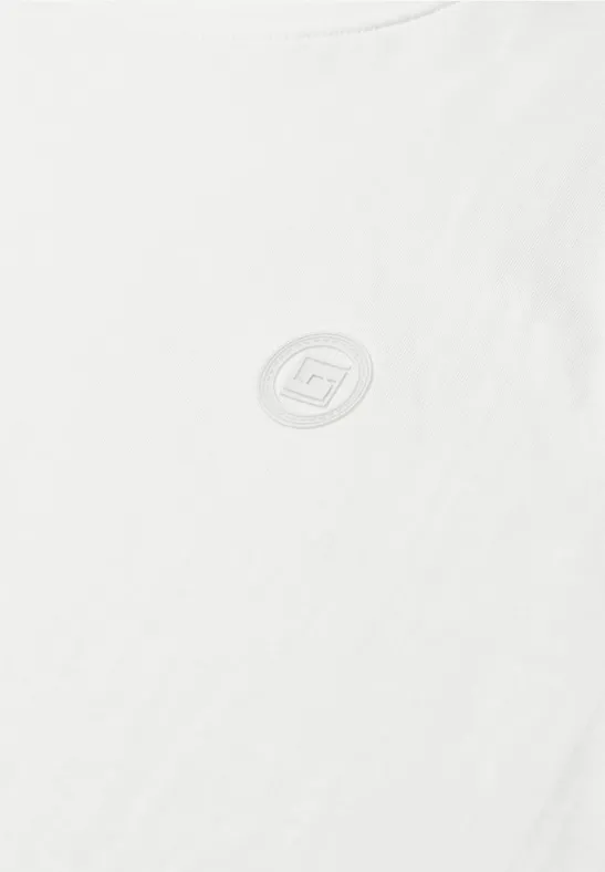 Een eenvoudig wit T-shirt met een klein rond logo op de borst.