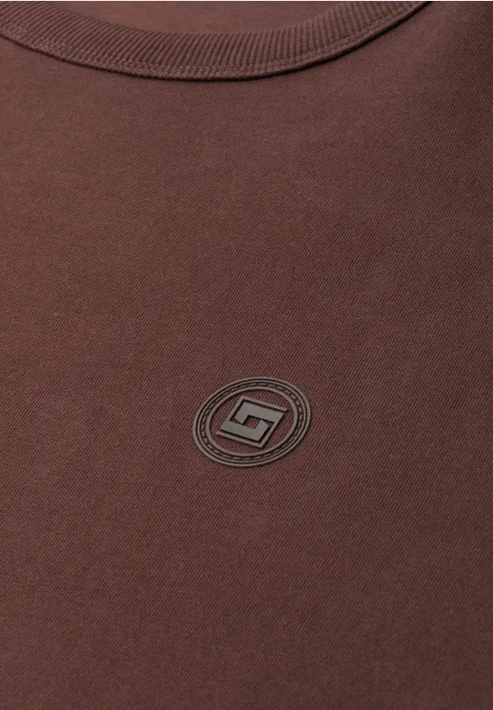 Braunes T-Shirt mit kleinem rundem Logo in der Mitte.