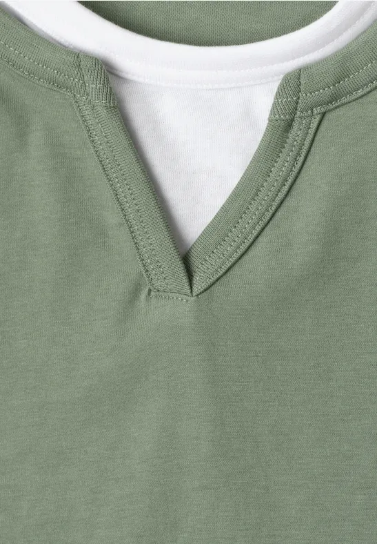 Close-up van een groen T-shirt met V-hals en een wit binnenlaagje.