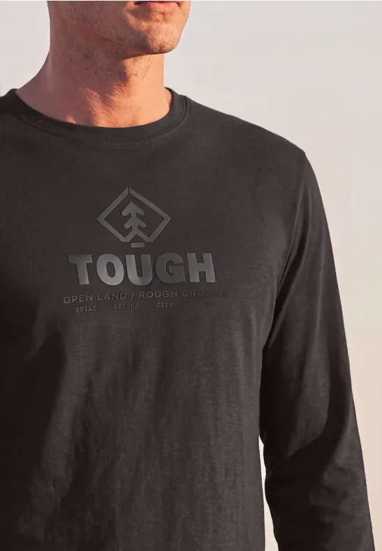 Mann trägt schwarzes Langarmshirt mit großem „TOUGH“-Aufdruck und stilisiertem Pfeil-Logo