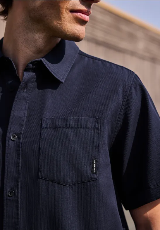 Gros plan d'un homme portant une chemise bleu marine à manches courtes avec une poche poitrine.