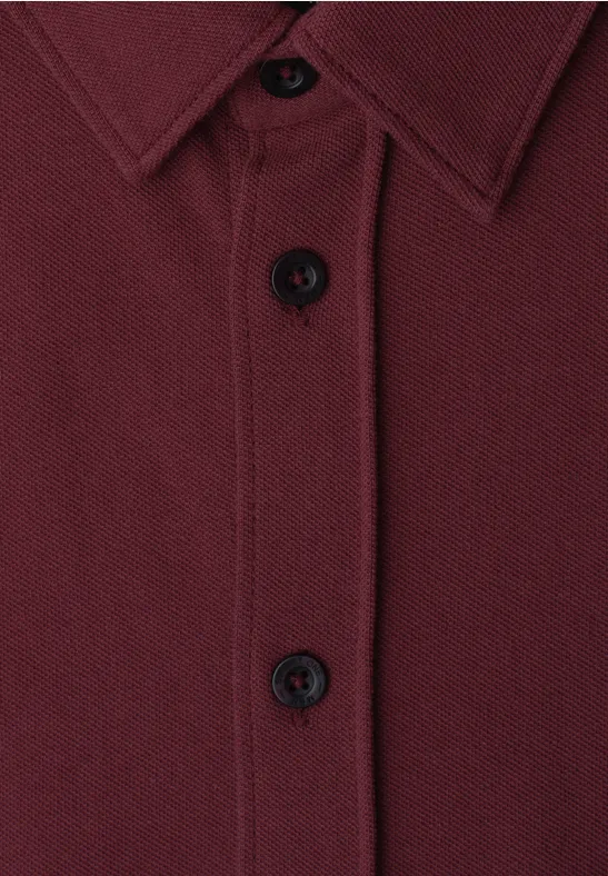 Nahaufnahme eines dunkelroten Hemds mit Knopfleiste und Kragen.