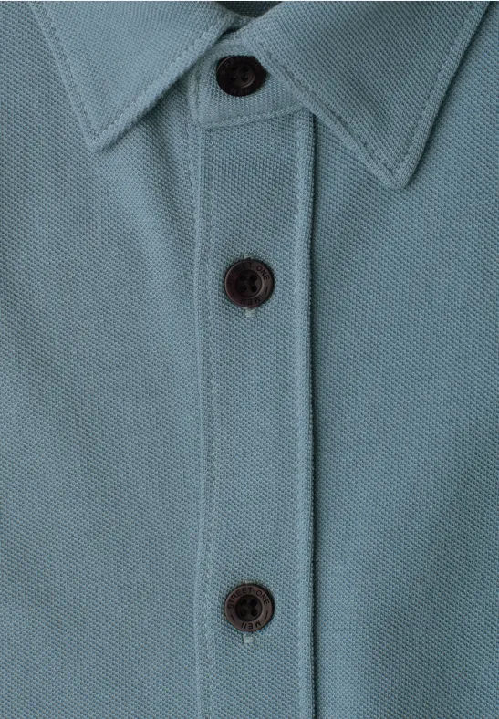 Nahaufnahme eines türkisfarbenen Poloshirts mit Kragen und drei schwarzen Knöpfen.