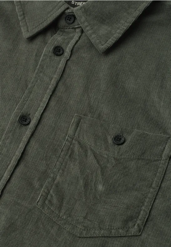 Close-up van een donkergroen corduroy overhemd met knoopsluiting en borstzak.