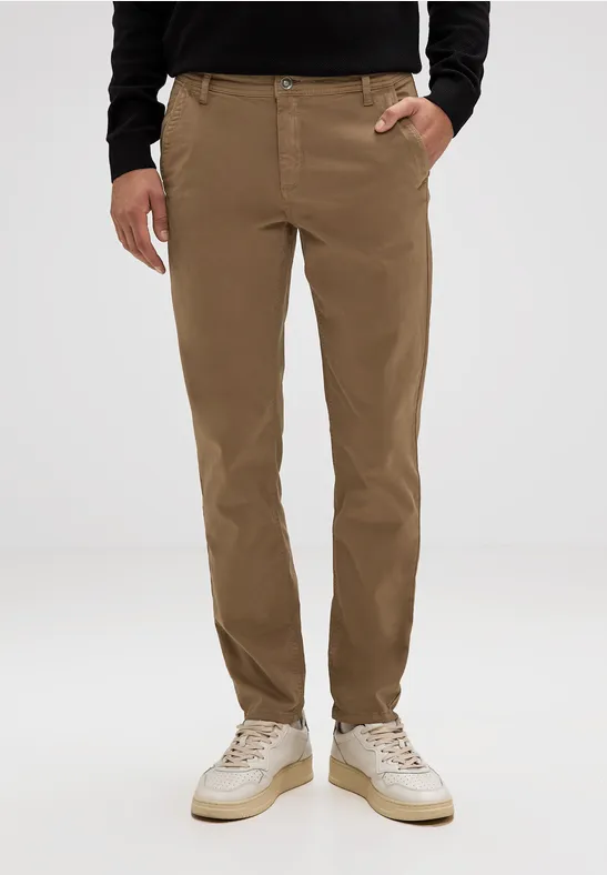 Mann trägt beige Chinohose, schwarzen Pullover und helle Sneaker.