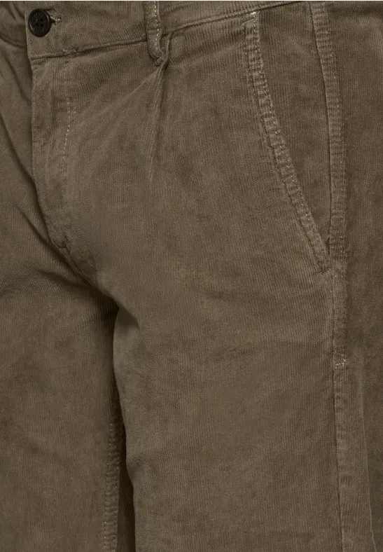 Gros plan sur un pantalon en velours côtelé marron avec poche latérale.