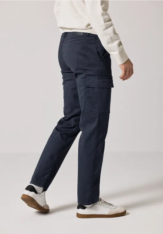 Person trägt dunkelblaue Cargohose und weiße Sneaker.