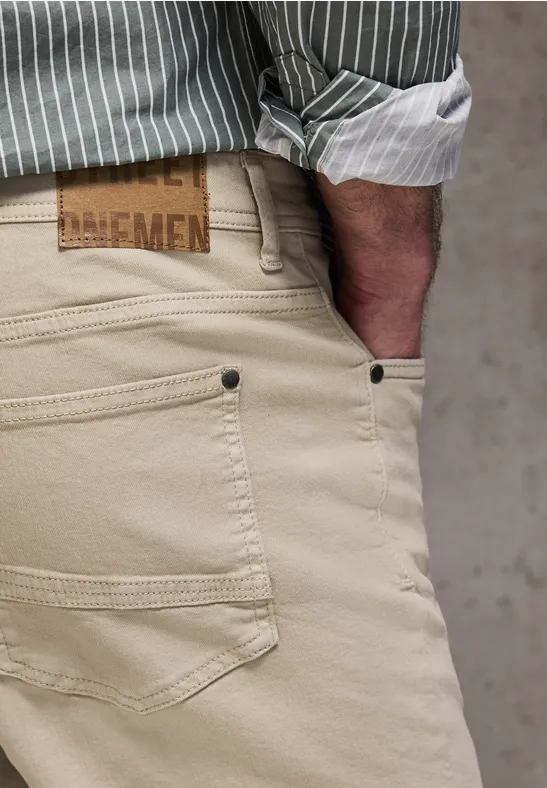 Nahaufnahme einer Person in beiger Hose und gestreiftem Hemd.
