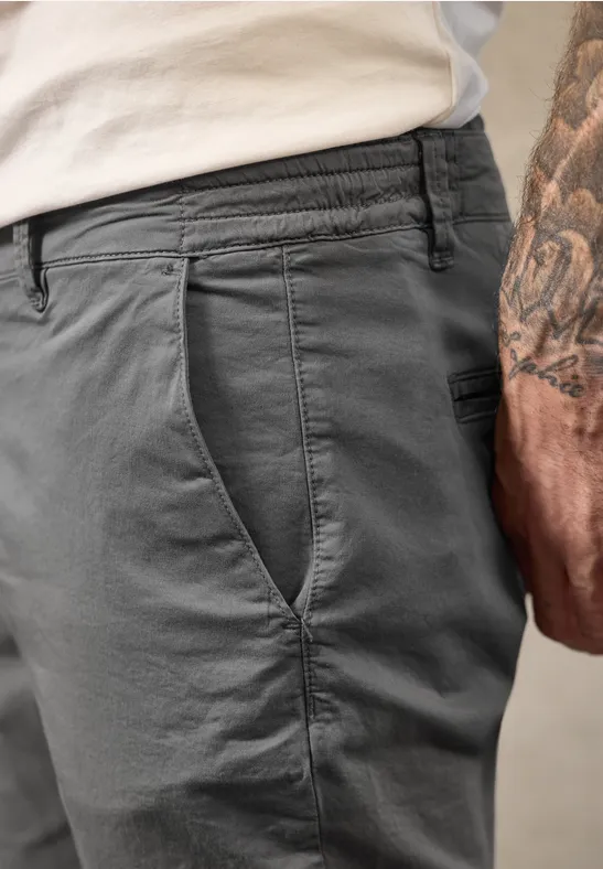 Seitliche Nahaufnahme einer dunkelgrauen Hose und tätowiertem Unterarm