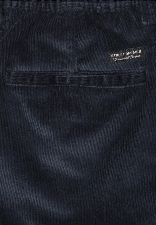 Nahaufnahme einer dunkelblauen Cordhose mit sichtbarer Naht und kleinem Logo-Etikett.