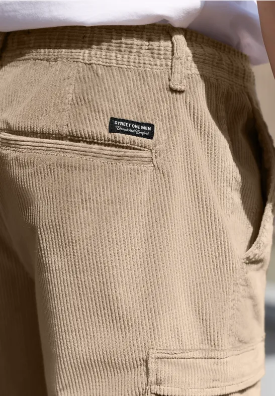 Nahaufnahme einer hellbeigen Cordhose mit Gesäßtasche und kleinem schwarzen Label.