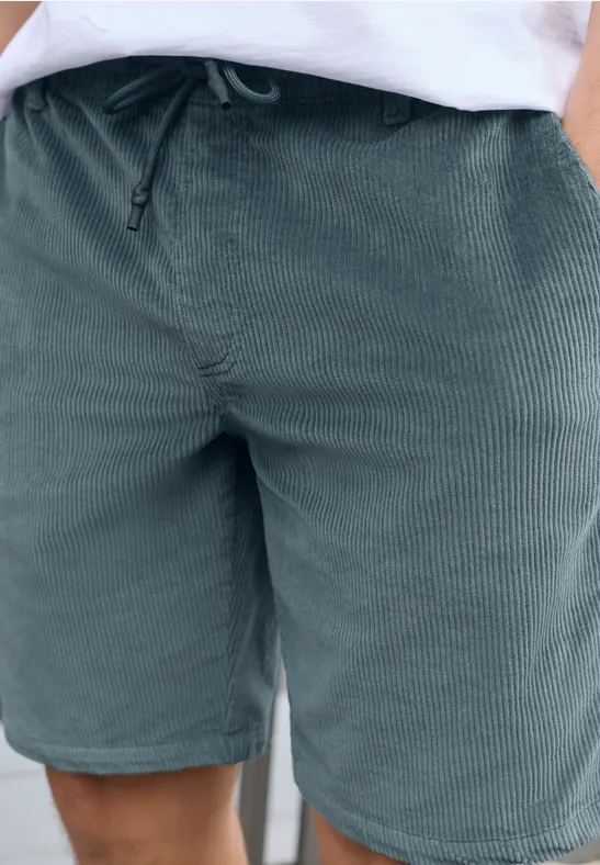 Grüne Cord-Shorts mit Tunnelzug und Taschen, kombiniert mit weißem Oberteil