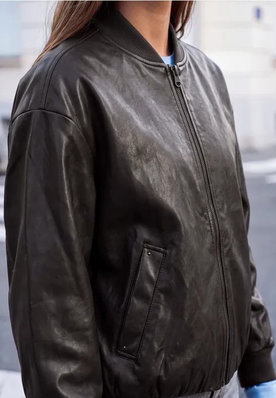 Schwarze Lederjacke im Bomberstil mit Reißverschluss, lässig geschnitten.