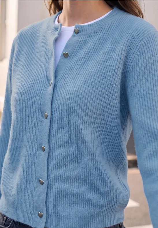 Hellblauer, gerippter Cardigan mit herzförmigen Knöpfen über weißem Shirt