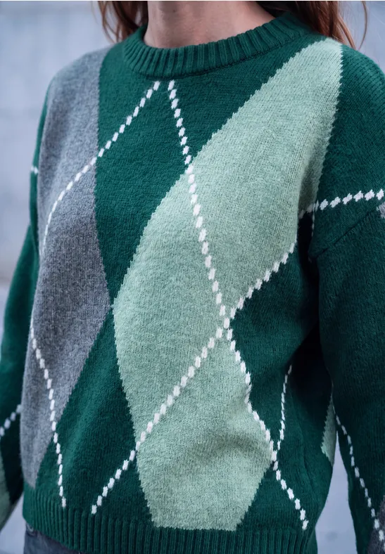 Grüner Rautenstrickpullover mit hell- und dunkelgrünen sowie grauen Keilen und weißen Linien.