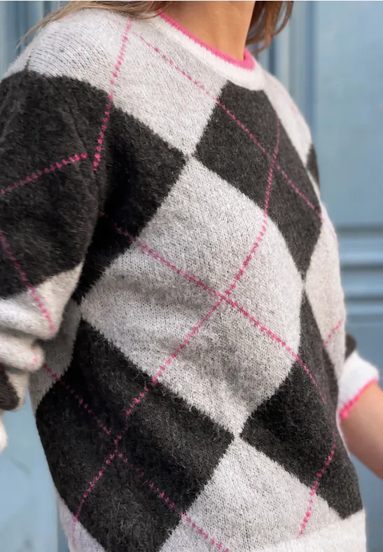 Nahaufnahme eines flauschigen Strickpullovers mit Rautenmuster in Schwarz, Weiß, Grau und rosa Akzenten.