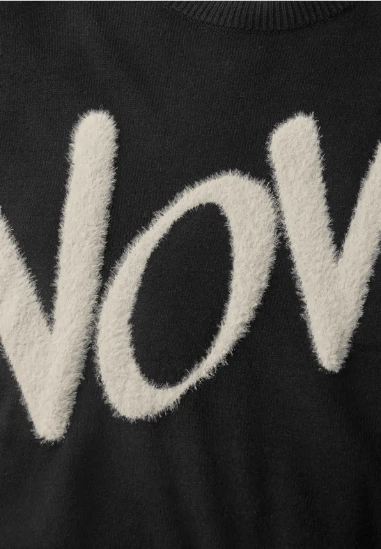 Schwarzes Kleidungsstück mit flauschigem "NOV"-Schriftzug in Creme.