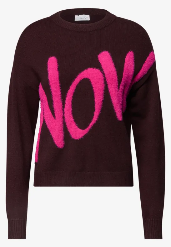 Pull bordeaux avec inscription rose fluo « NOW » en grosses lettres.