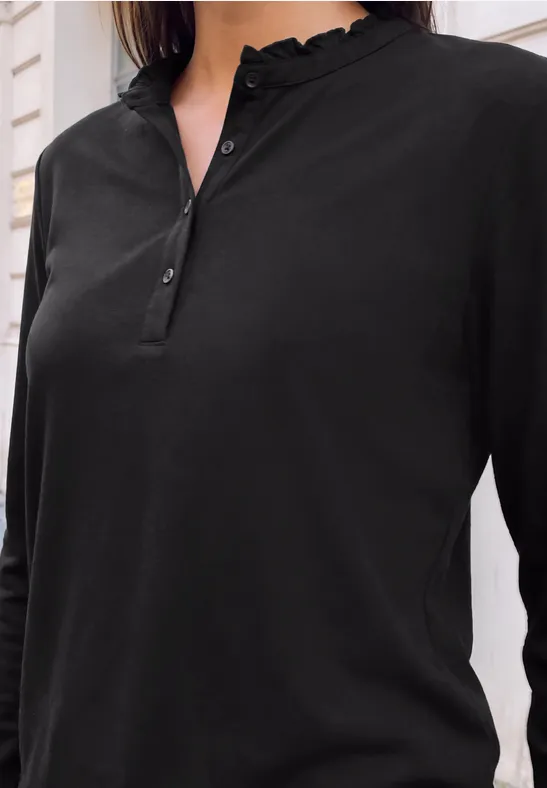 Schwarzlangärmeliges Henley-Shirt mit Rüschenkragen, Knopfleiste und schmaler Passform vor hellem Hintergrund.