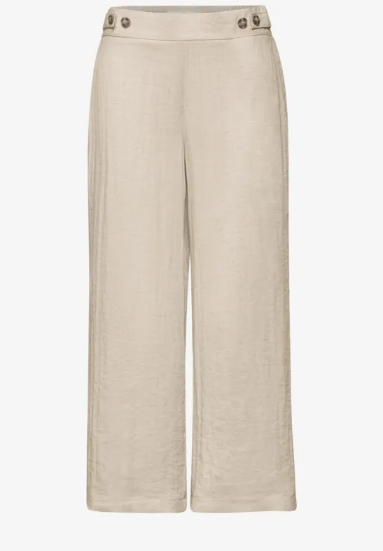 Beige Leinenhose mit weitem Bein, hoher Taille und Knopfdetails am Bund.