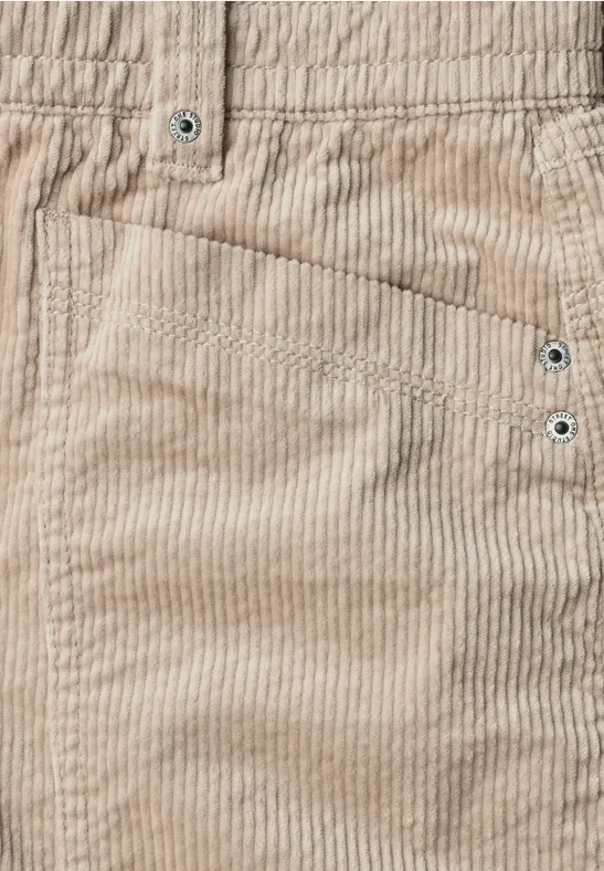 Nahaufnahme einer hellbeigen Cordhose mit sichtbarer Tasche und Ziernähten.