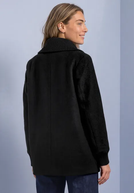 Mantel mit Wollanteil und Strickkragen Black Frau mit schwarzem Mantel und hohem Kragen, Aufnahme von hinten.