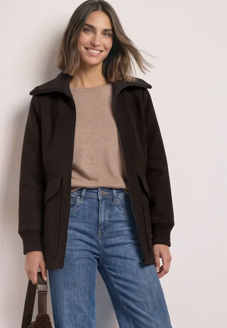 Mantel mit Wollanteil und Strickkragen auburn brown Eine lächelnde Frau in Jeans und brauner Jacke vor hellem Hintergrund.