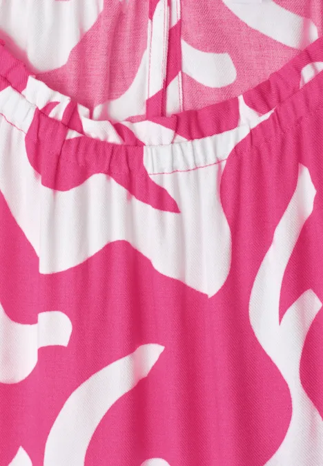 Gros plan d’un tissu rose et blanc à motif abstrait avec un col élastique.