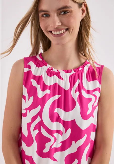 Enfant porte un haut sans manches rose et blanc à motif abstrait.