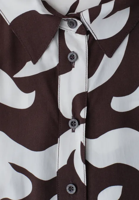 Gros plan d'une chemise à motif abstrait noir et blanc avec boutons noirs.