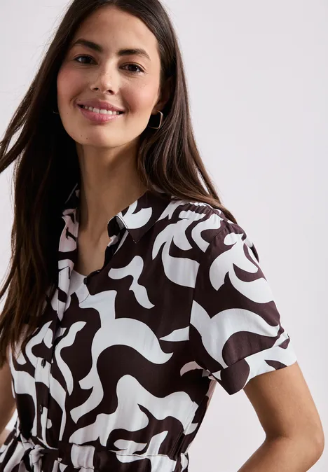 Femme en chemisier manches courtes à motif abstrait noir et blanc sur fond blanc