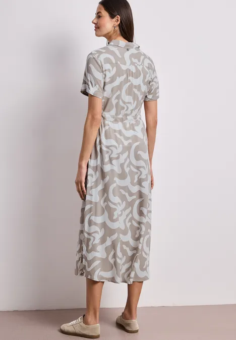 Femme de dos portant une robe midi beige à motifs abstraits, manches courtes et col montant