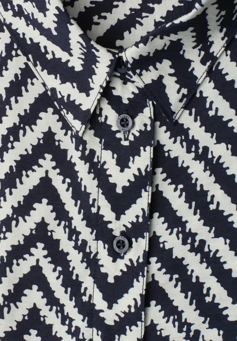 Gros plan d’une chemise à motif zigzag noir et blanc avec boutons et col.