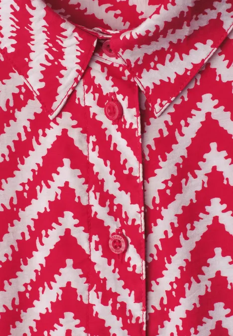 Chemise rouge à motif zigzag blanc, patte de boutonnage apparente.