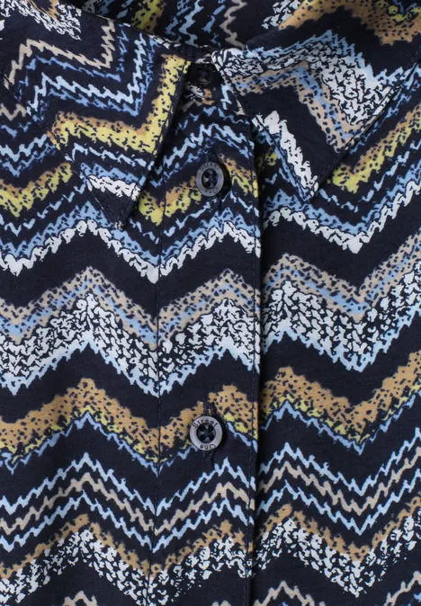 Nahaufnahme einer Strickjacke mit Zickzackmuster in Blau, Weiß, Gelb und Schwarz und Knöpfen.
