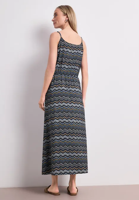 Frau von hinten in ärmellosem langen Maxikleid mit buntem Zickzackmuster.