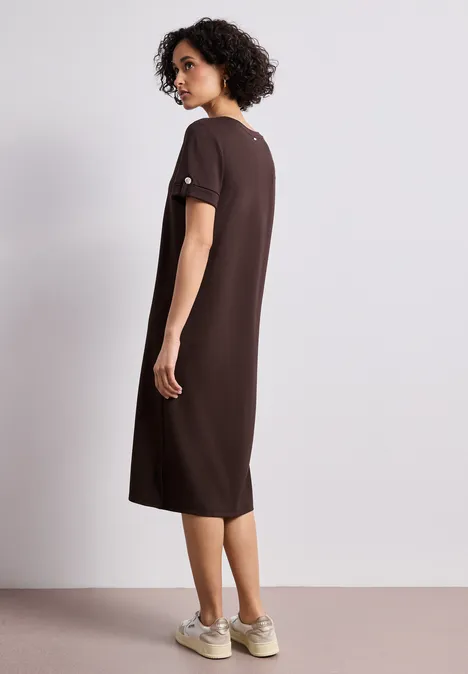Midi-Kleid mit Rundhals und Knöpfen espresso brown Frau von hinten in lockerem braunem Midi-Kleid und Sneakern, auf neutralem Hintergrund.