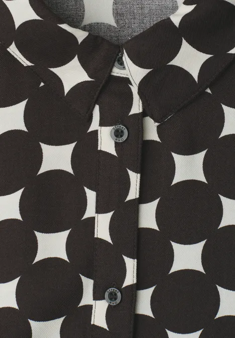 Hemd mit schwarz-weißen geometrischen Kreisen und Sternen, mit Kragen und Knöpfen.
