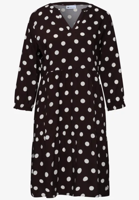 Schwarzes Kleid mit weißen Punkten, V-Ausschnitt und 3/4-Ärmeln.