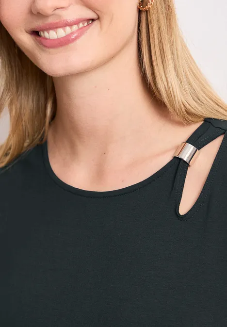 Femme aux cheveux blonds souriant portant un top noir à ouverture à l’épaule et anneau métallique