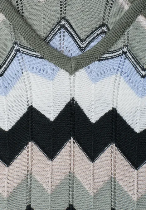 Nahaufnahme eines gestrickten Pullovers mit Zickzackmuster in Grau, Hellblau, Weiß, Schwarz und Beige.