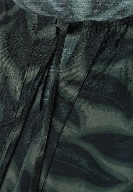 Nahaufnahme eines dunkelgrünen Camouflage-Stoffs mit schwarzen Mustern und Kordeln