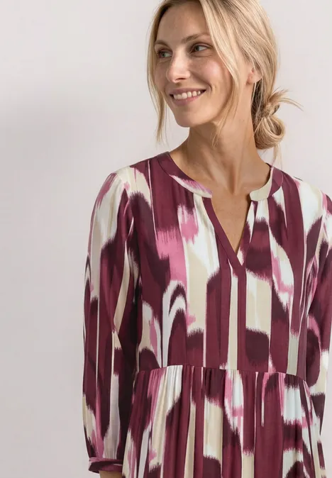 Midi-Kleid mit Split Neck im Ethno-Look rustic rouge Frau in locker geschnittenem Kleid mit lila-weißen abstrakten Pinselstrich-Mustern.