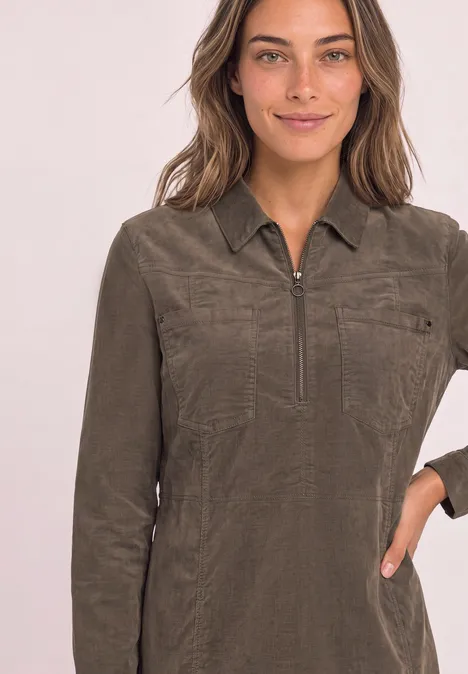 Frau trägt khakifarbenes Langarm-Shirt mit Reißverschluss, Kragen und Brusttaschen.